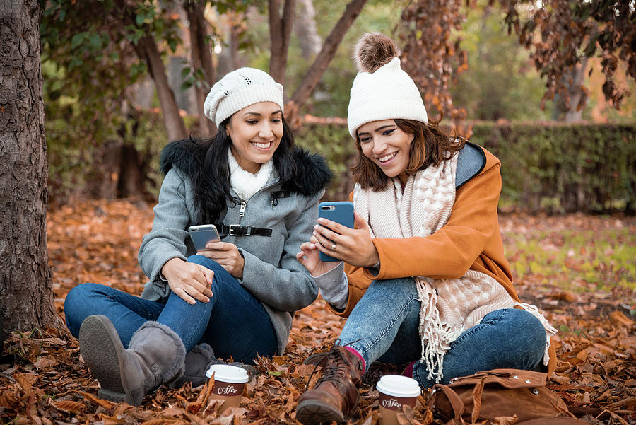 Coffee Photograph - Two Old Girl Friends Looking At The Smartphone Screen Together. Close Up Of Two Old Girl Friends And The Park Background In The Fall. by Cavan Images