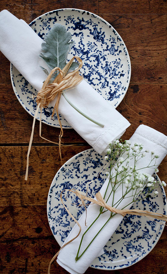 Two Place Settings With Blue And White Plates, And White Napkins Tied ...