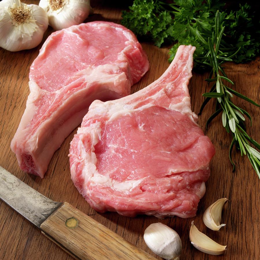 Two Raw Veal Chops With Herbs And Garlic On Cutting Board Photograph by Paul Poplis