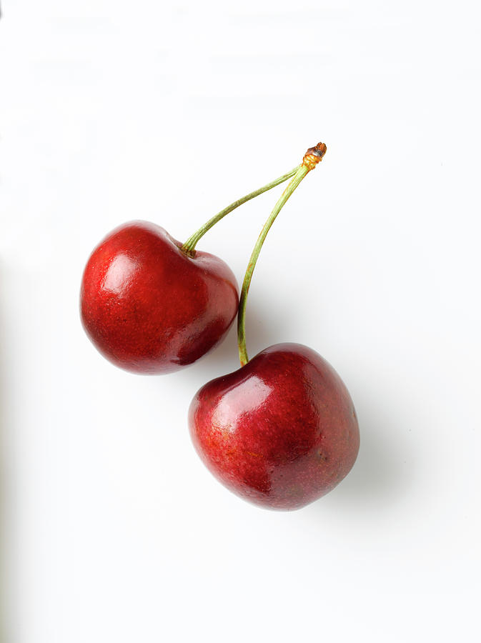 Two Red Cherries On A White Surface Photograph by Howard Bjornson