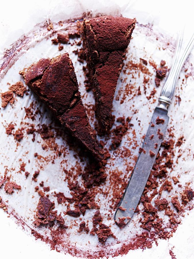 Two Slices Of Chocolate Cake On A Plate With Cake Crumbs And A Knife Photograph by Oliver Brachat