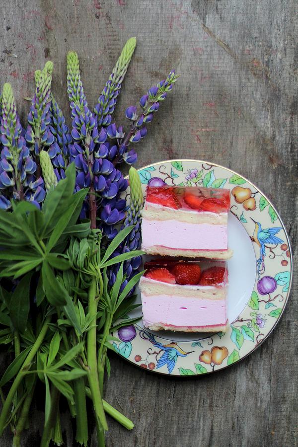 Two Slices Of Strawberry Cake On A Plate Next To Lupin Flowers Photograph by Sylvia E.k Photography