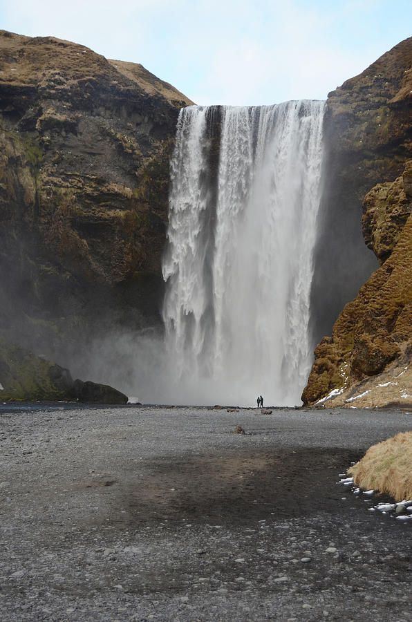 Two Tourists Admiring the Towering Skogafoss Waterfall Iceland Photograph by Shawn OBrien