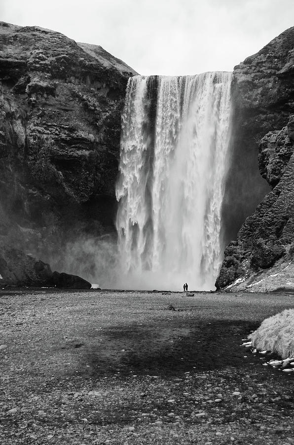 Two Tourists Silhouetted Against the Towering Skogafoss Waterfall Iceland Black and White Photograph by Shawn OBrien