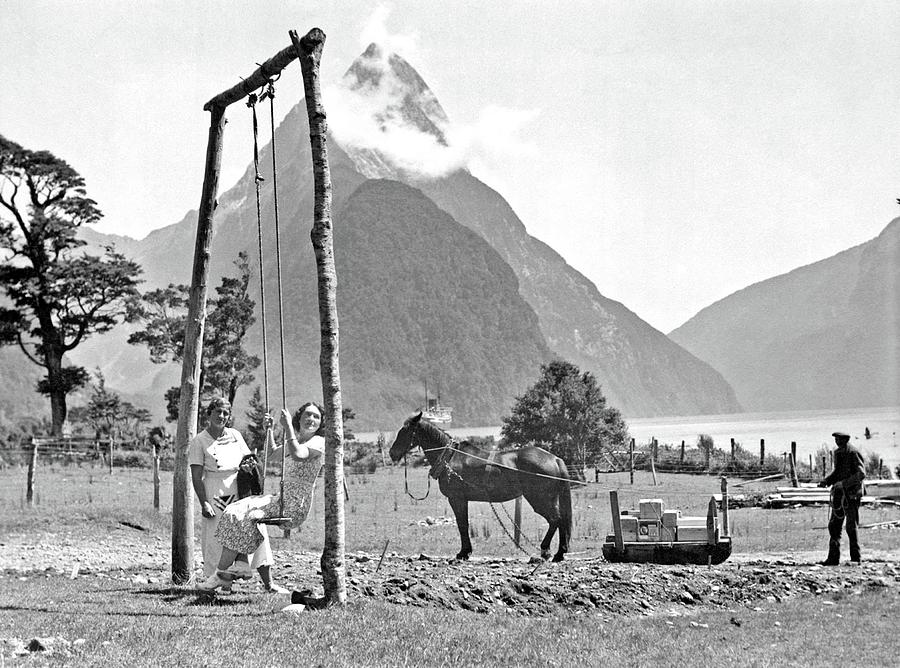 Two unidentified women on a swing, and a man unloading stores, Milford Sound, 1930s Painting by Celestial Images