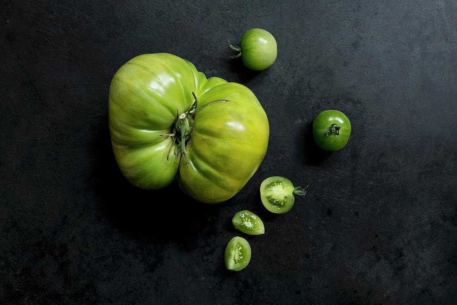 Two Varieties Of Green Tomatoes On A Dark Metal Surface varieties: Green Doctor And Absinthe Photograph by Sabine Lscher