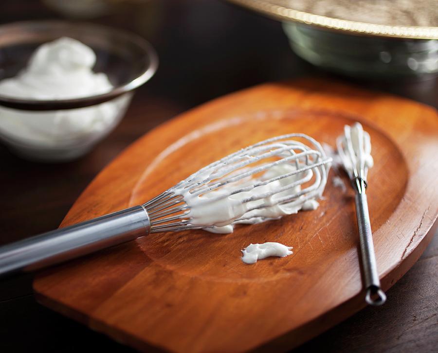 Two Whisks With Freshly Whipped Cream On A Wooden Board Photograph by Katharine Pollak
