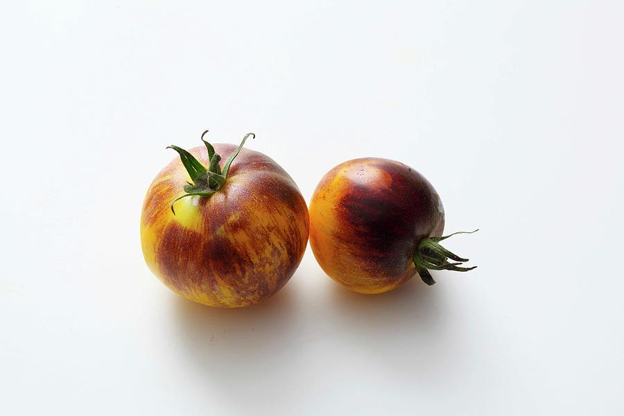 Two Yellow-and-black Tomatoes On A White Surface Photograph by Jalag / Mathias Neubauer