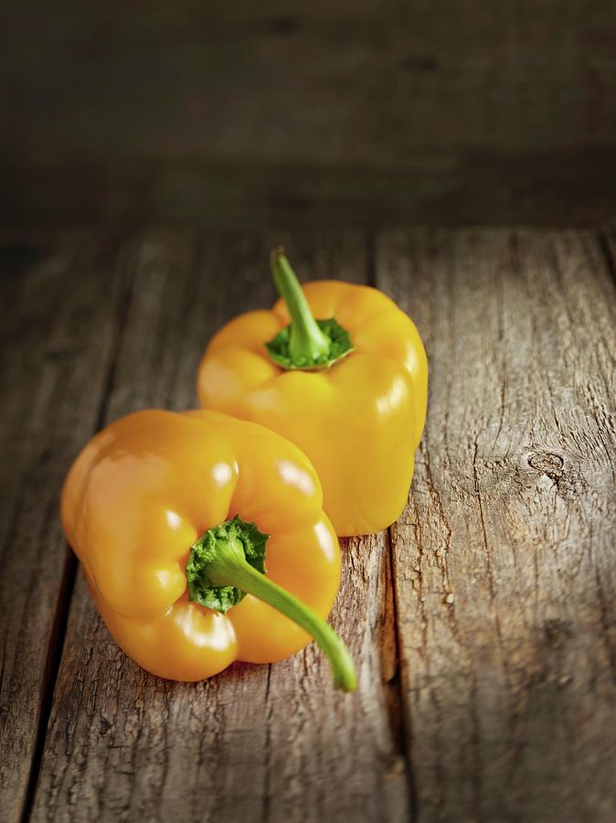 Two Yellow Peppers On A Wooden Surface Photograph by Michael Lffler