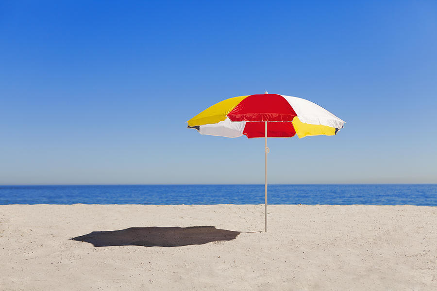 Umbrella In Sand On Empty Beach Photograph by Hybrid Images