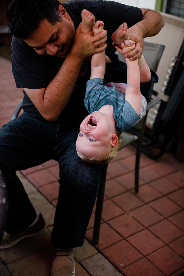 San Diego Photograph - Uncle Holding Nephew Upside Down In Yard In San Diego by Cavan Images