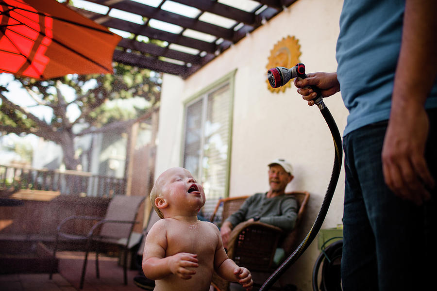 San Diego Photograph - Uncle Spraying Nephew With Hose As Grandpa Smiles In San Diego by Cavan Images