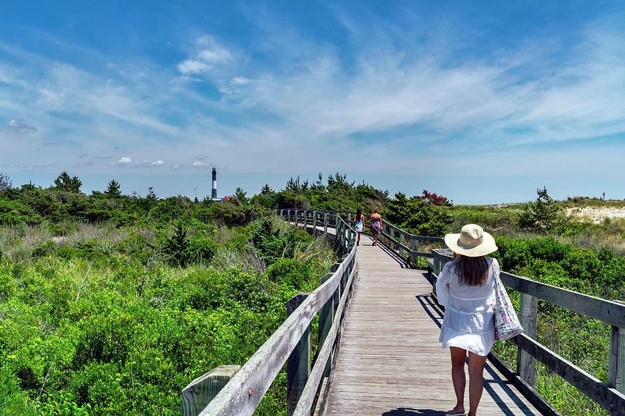 Usa, New York, Long Island, People Walking On A Wooden Path To Fire Island Lighthouse Surrounded By Grass And Green Trees. Digital Art by Alejandra Uribe Posada
