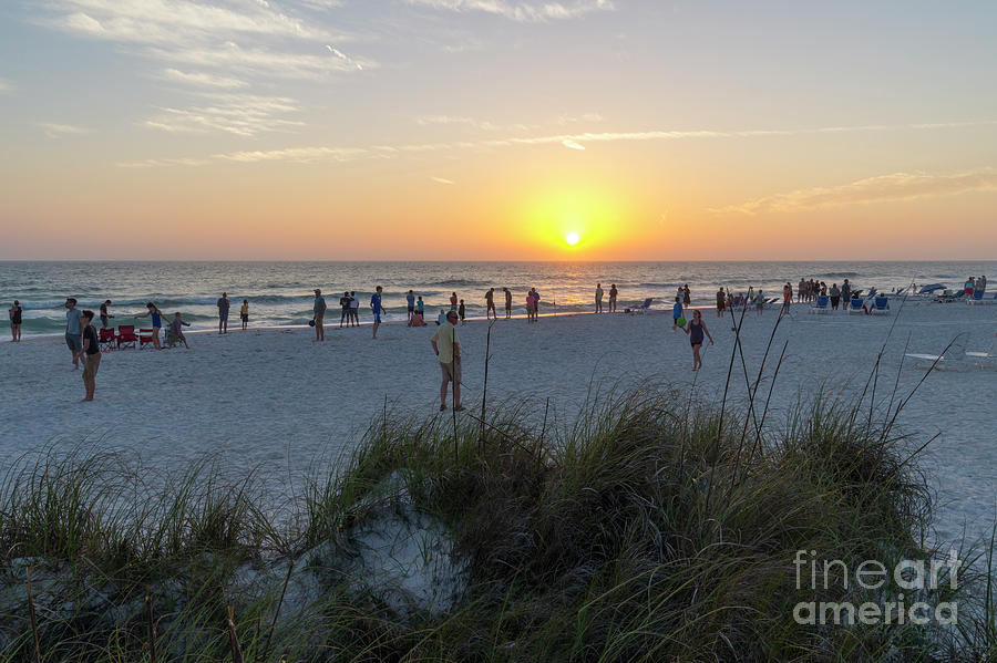 Vacationers gather to watch the sunset along the beach on Anna M Photograph by William Kuta