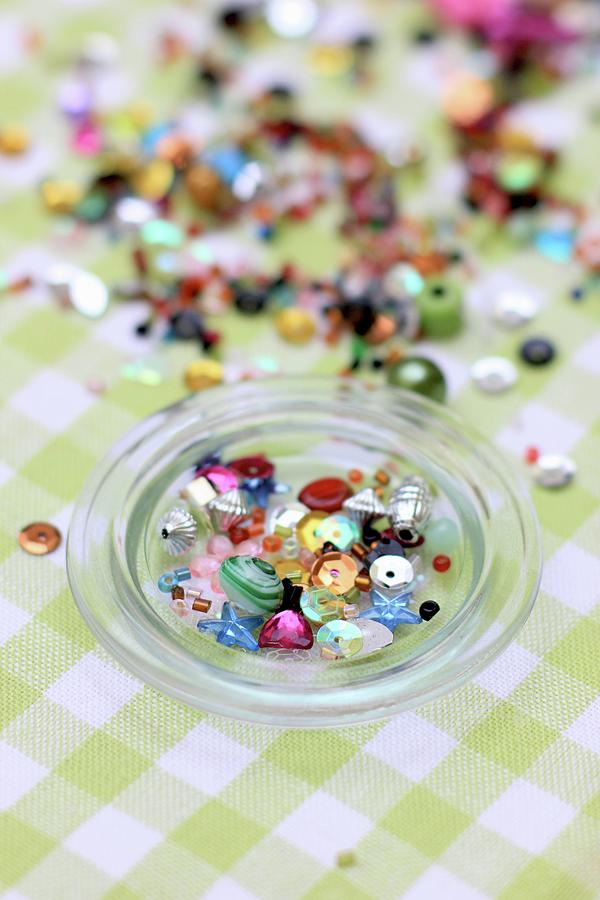 Various Beads In And Next To Glass Bowl Photograph by Ruth Laing