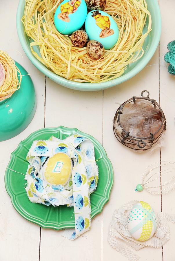 Various Easter Nests Of Eggs, Raffia And Ribbons In Bowls And On Pale Wooden Surface Photograph by Revier 51