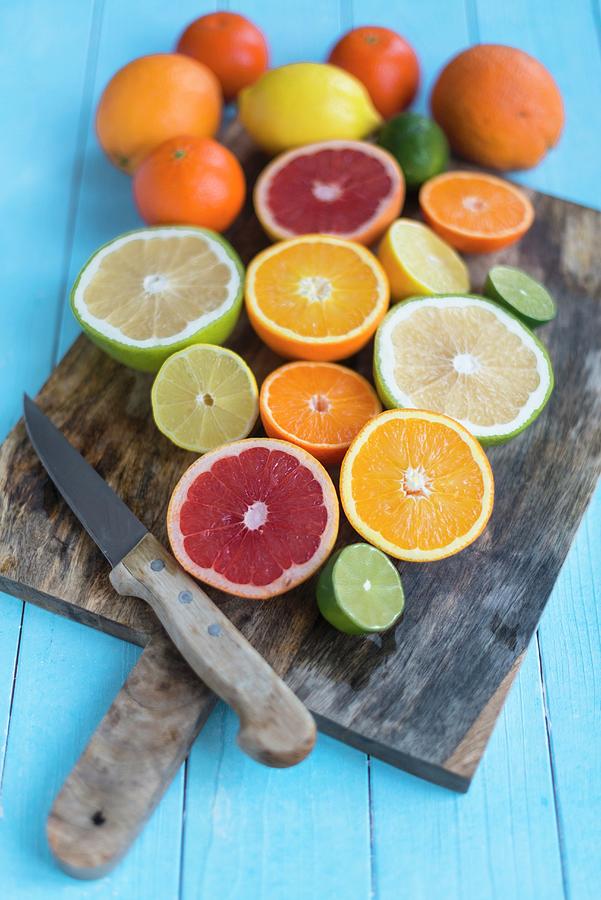 Various Halved Citrus Fruits On A Chopping Board With A Knife Photograph by Sebastian Schollmeyer