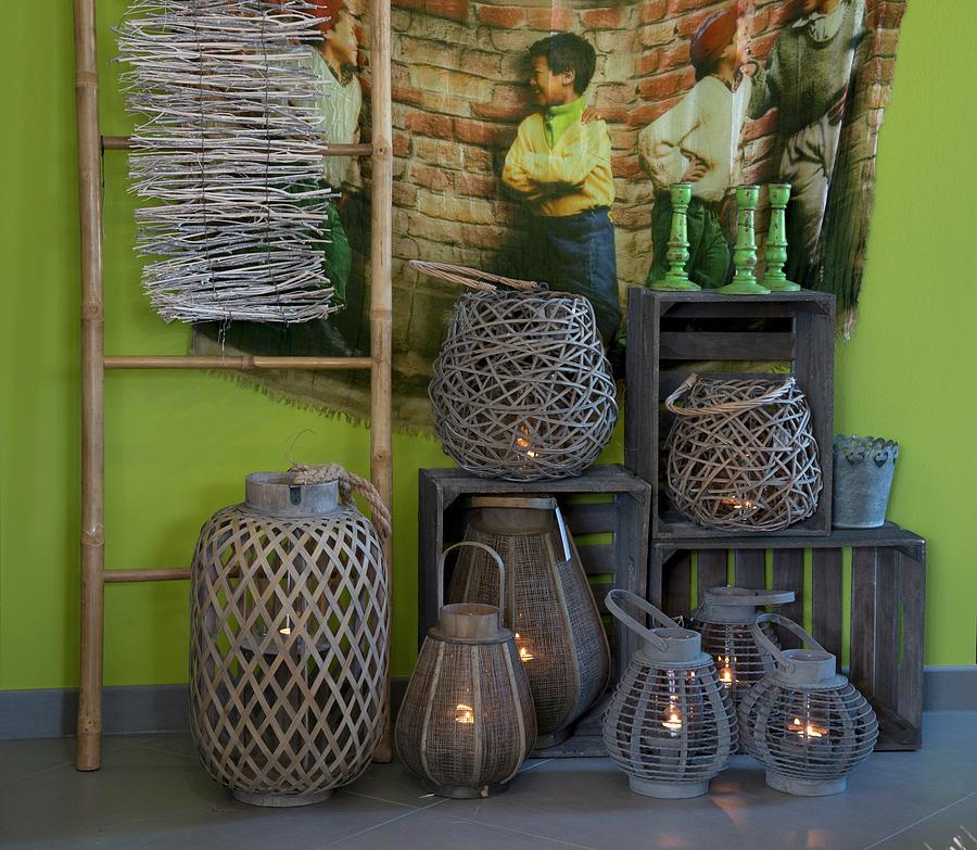 Various Lanterns And Wooden Crates Below Wall-hanging With Picture Of Children On Green Wall Photograph by Inge Ofenstein