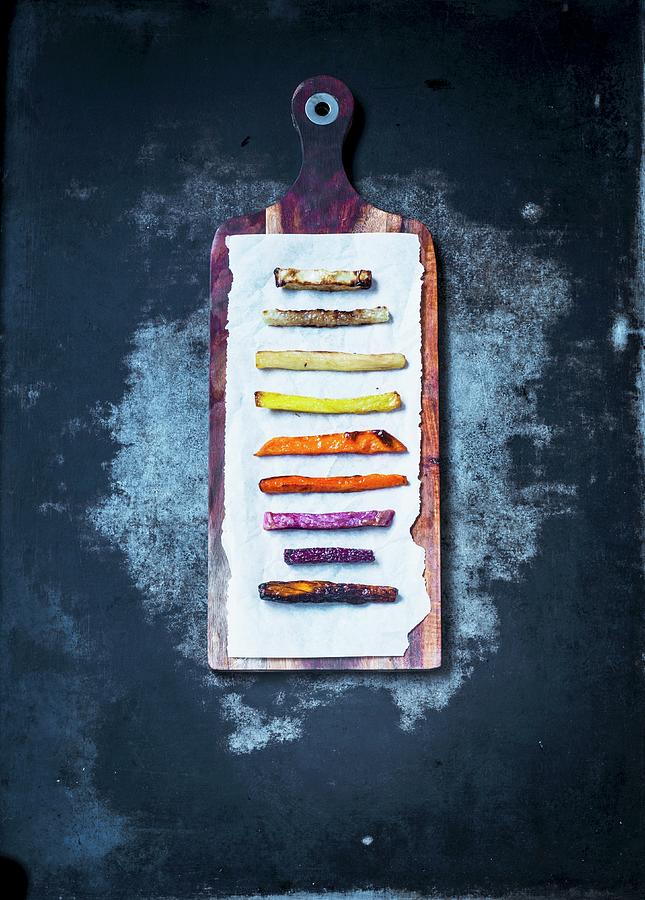 Various Vegetable Fries Lined Up On Paper On A Wooden Board Photograph by Carolin Strothe
