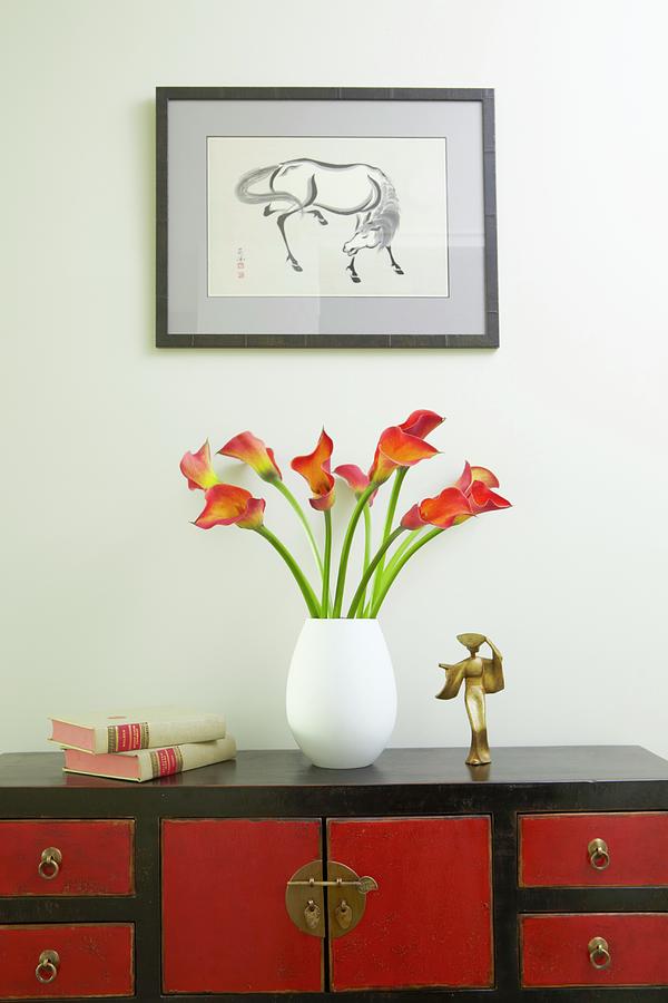 Lily Photograph - Vase Of Calla Lilies On Red And Black, Oriental-style Sideboard Below Framed Drawing Of Horse On Wall by Anastassios Mentis Photography