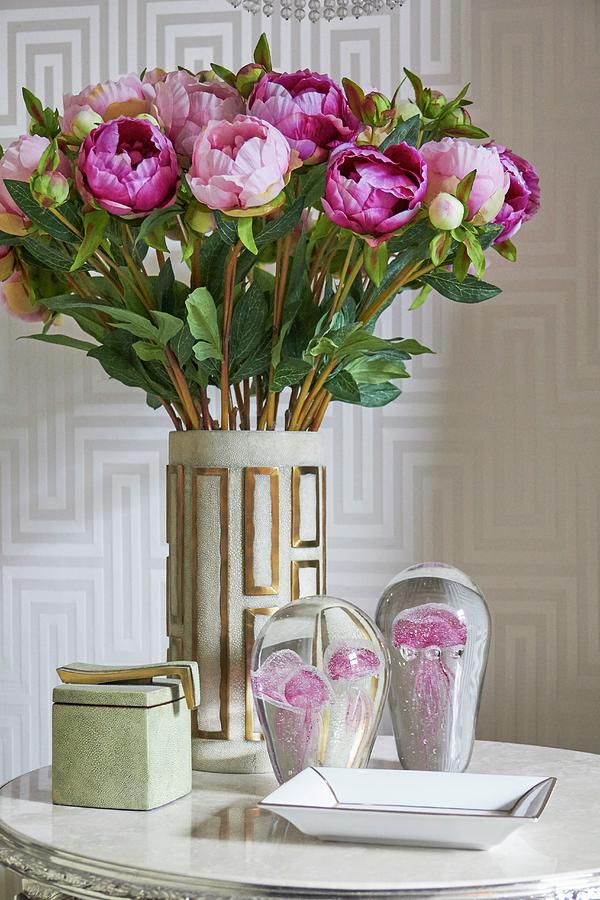 Vase Of Peonies And Glass Ornaments On Side Table In Front Of Patterned Wallpaper Photograph by Misha Vetter