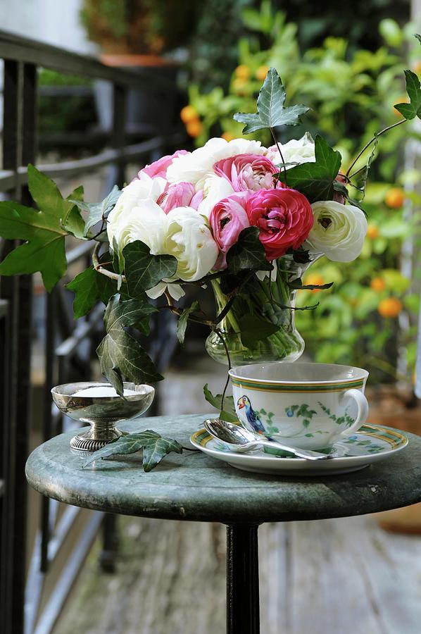 Vase Of Ranunculus And Cup And Saucer On Table On Balcony Photograph by Madamour, Christophe