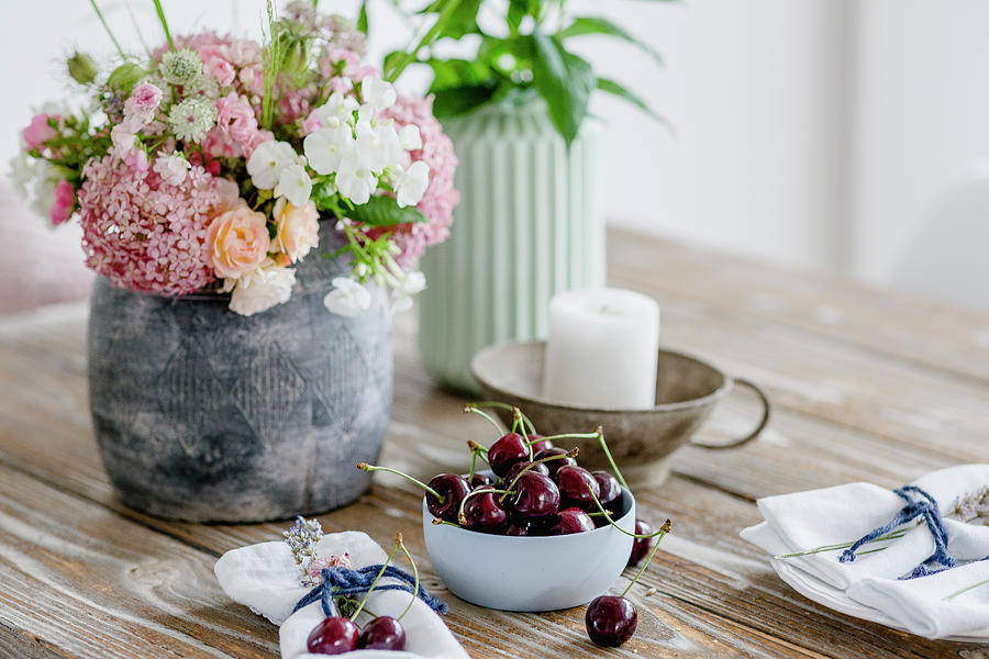 Vase Of Summer Flowers, Small Bowl Of Cherries And Candle On Wooden Table Photograph by Christel Harnisch