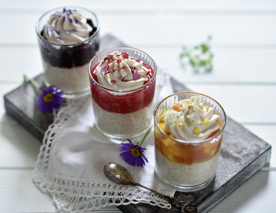 Vegan Rice Pudding Desserts In Glasses With Apricot-mango, Raspberry-rhubarb, And Blueberry Sauce Decorated With Coconut Cream And Flowers Photograph by B.b.s Bakery