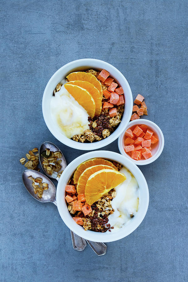 Vegetarian Breakfast Yogurt Bowls With Tasty Granola, Orange, Dried Fruit, Nuts And Seeds Over Grey Background, Top View Photograph by Yuliya Gontar