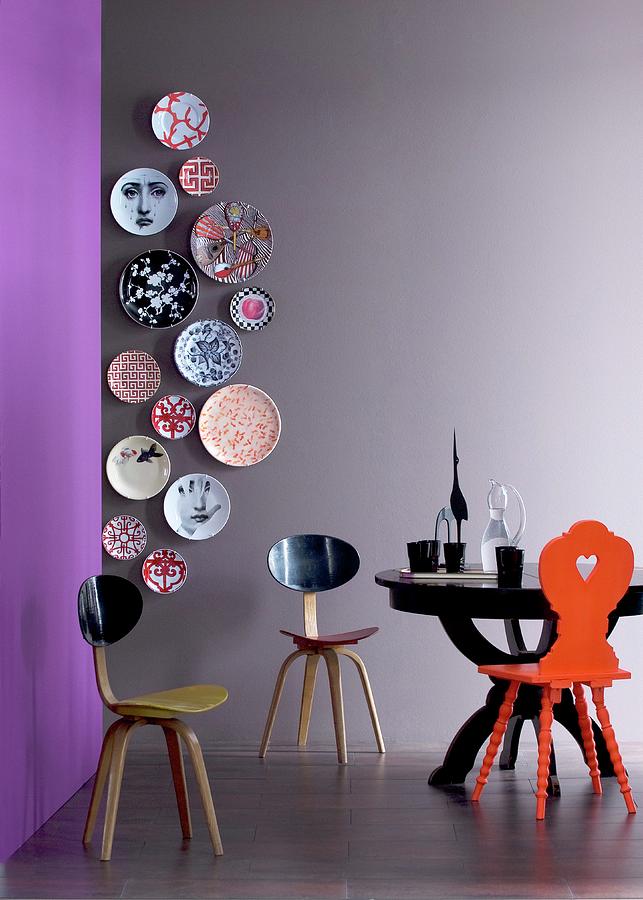 Vertical Arrangement Of Designer Wall Plates On Grey Wall, Designer Chair And Black Round Table Photograph by Matteo Manduzio