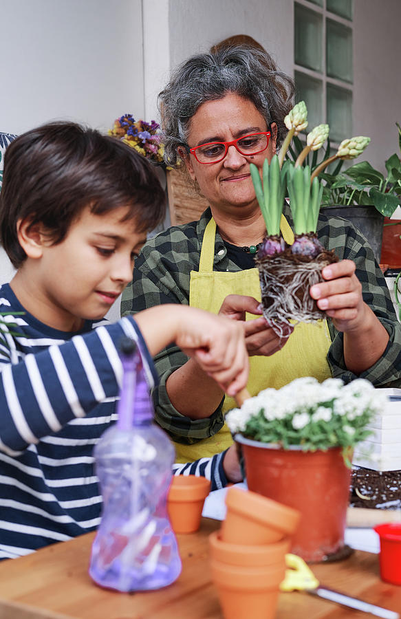 Nature Photograph - Vertical Photo Of A Child Learning With His Mother To Prepare The Plants For The Home Garden In Spring by Cavan Images