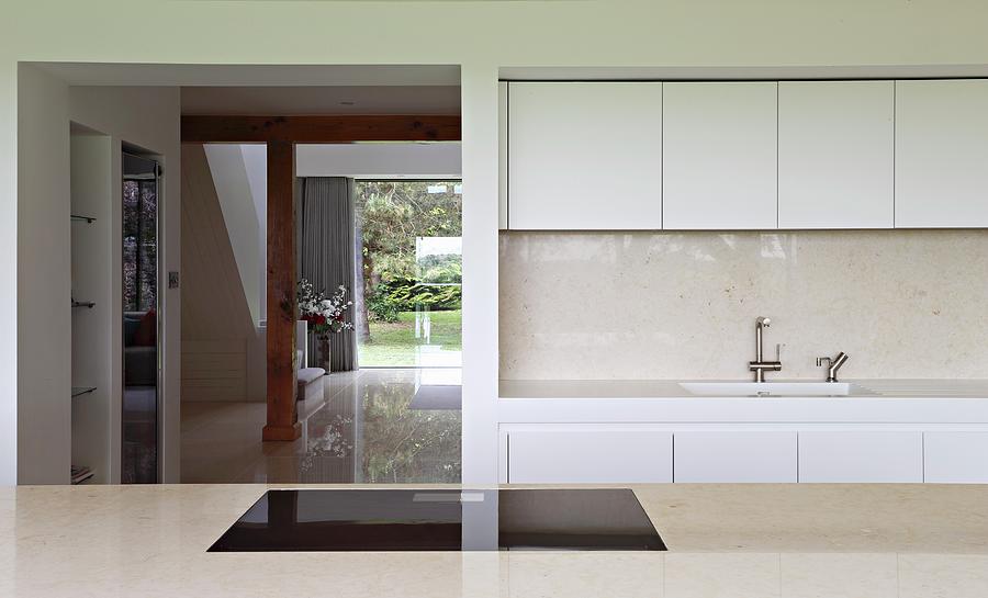 View Across Counter To Modern White Fitted Kitchen And Open Doorway ...