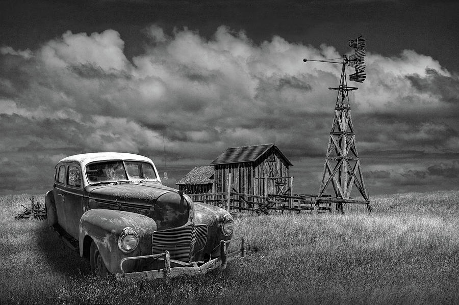 Vintage Automobile and Wooden Barn with Windmill in Black and White Photograph by Randall Nyhof