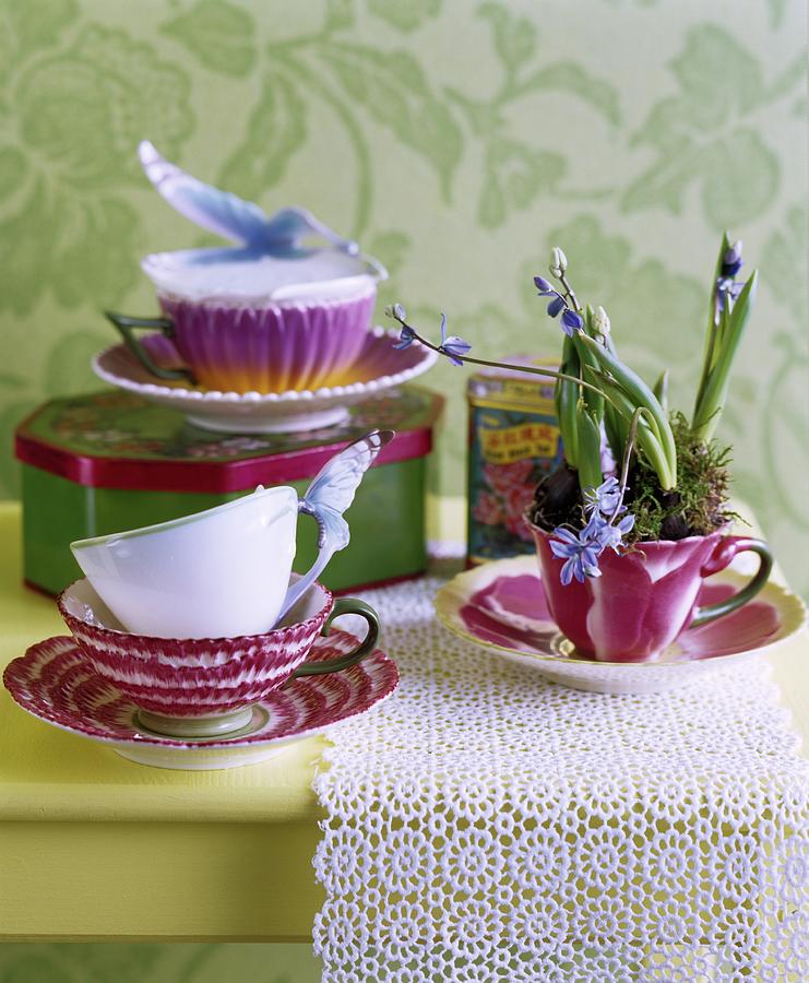 Vintage-style China Cups And Tin On Lace Doily On Table Photograph by Matteo Manduzio
