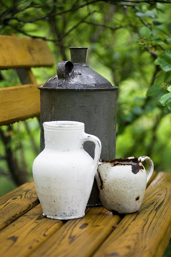 Vintage-style, Still-life Arrangement Of White Jugs And Canister On Wooden Bench In Garden Photograph by Alicja Koll