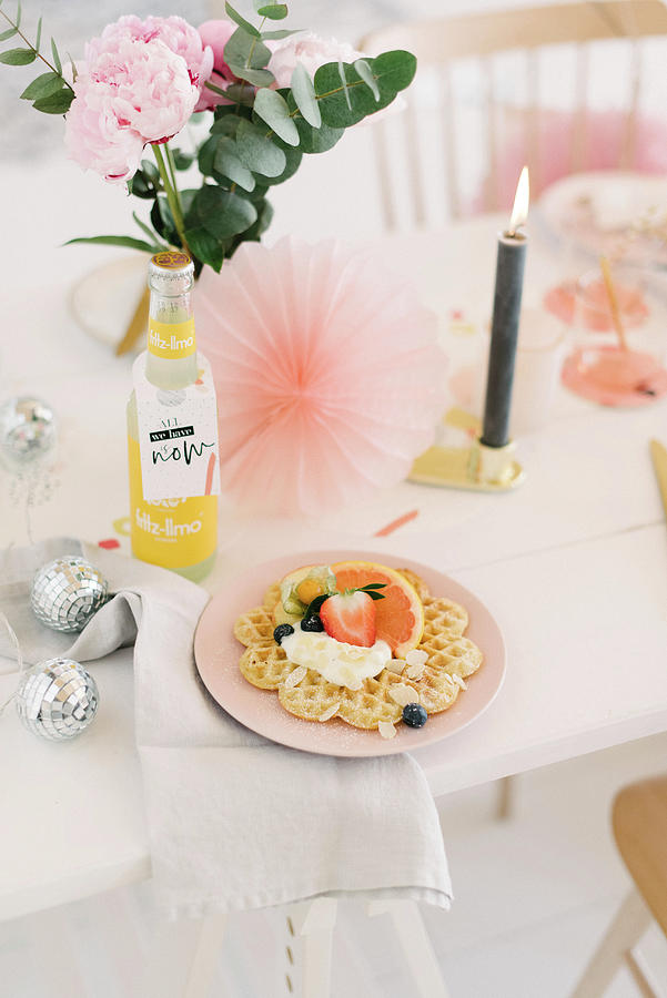 Waffle And Fruit On Table Festively Decorated With Glittery Balls, Candle And Paper Rosettes Photograph by Katja Heil