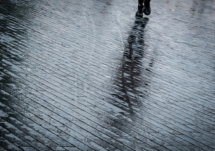 Walking shadow of an unrecognised person walking on wet streets  Photograph by Michalakis Ppalis