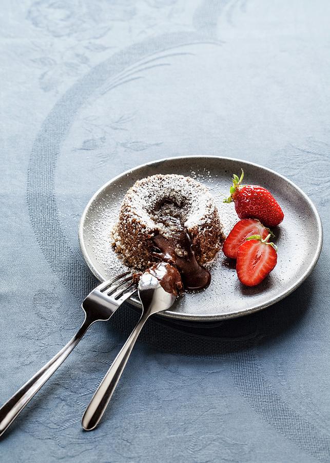 Warm Chocolate Cake With A Liquid Core Dusted With Icing Sugar And Served With Strawberries Photograph by Julia Hildebrand