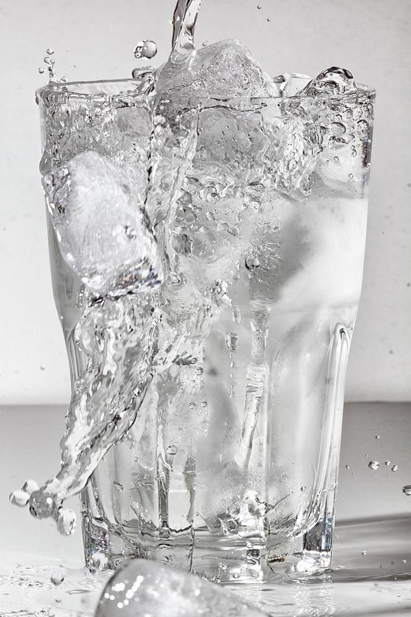 Water Being Poured Into A Glass Of Ice Cubes Photograph by Uwe Merkel