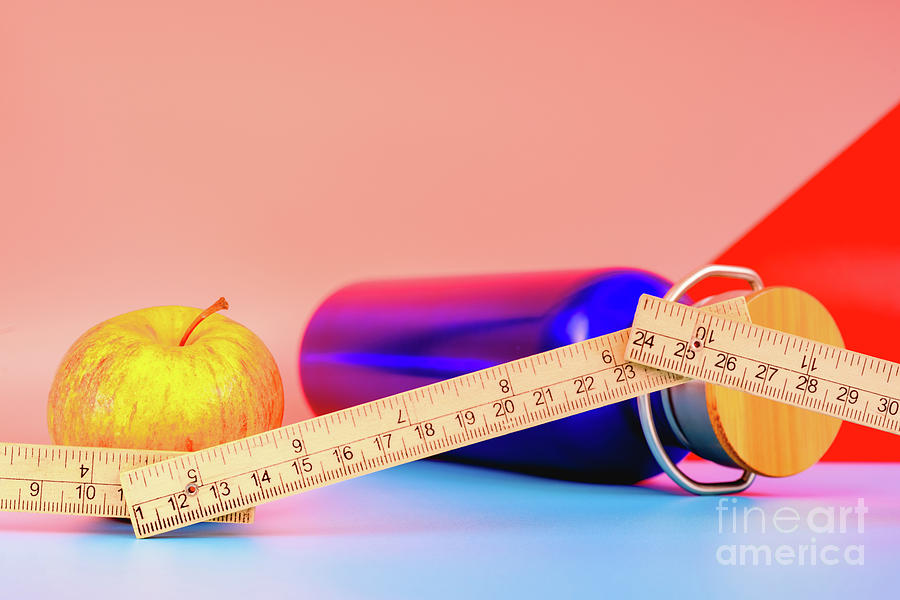 Water bottle, apple and measuring tape isolated on colorful background in studio, healthy life concept. Photograph by Joaquin Corbalan