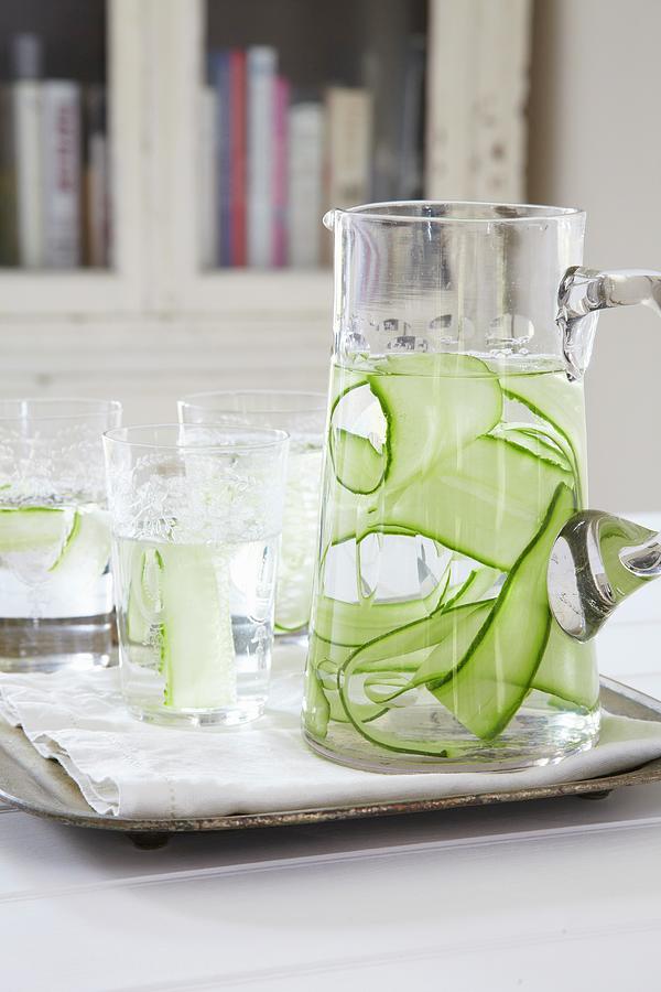 Water With Cucumber Strips In A Carafe And In Glasses Photograph by Simon Scarboro