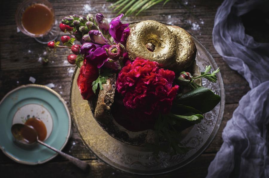 Wedding Cake Decorated With Fresh Flowers And Gold Donuts On Table Setting With Salted Caramel Sauce. Photograph by Rose Hewartson