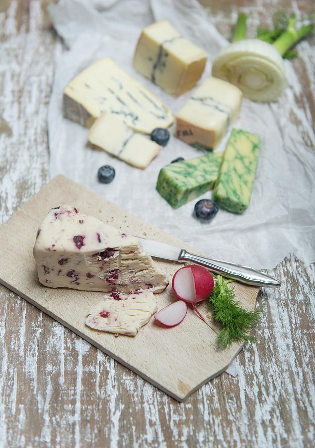 Wensleydale, Jacobean Sage, Cambozola, Morbier With Fennel, Radishes And Blueberries On A Wooden Board And A Piece Of Paper Photograph by Angelika Grossmann