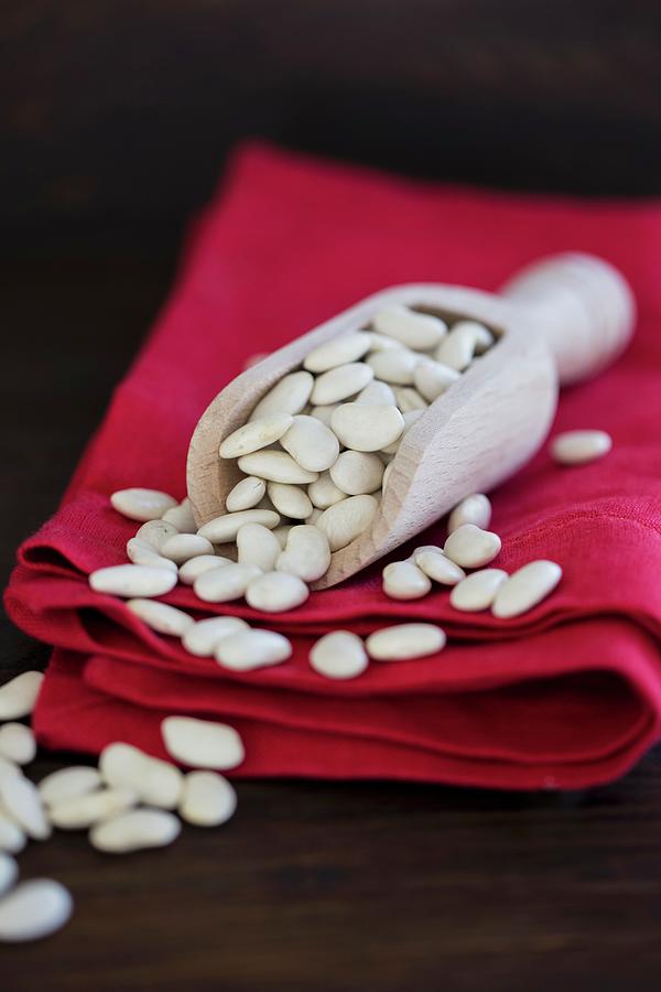 White Beans In A Wooden Scoop On Red Napkins Photograph by Nicole Godt