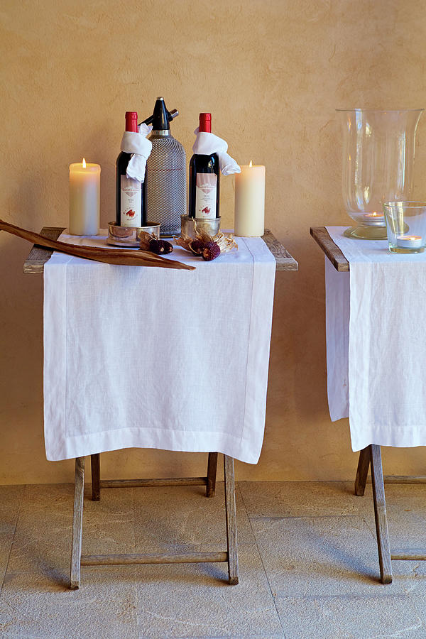 White Cloths, Wine Bottles And Candles On Two Folding Tables Photograph by Sven C. Raben