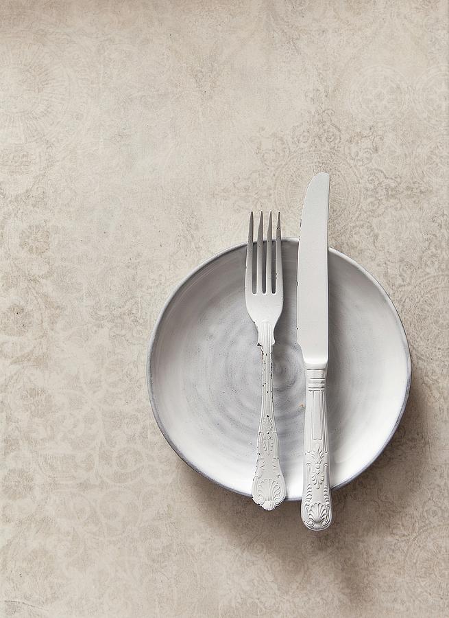 White Cutlery On A White Plate On A Textured Stone Surface Photograph by Stacy Grant