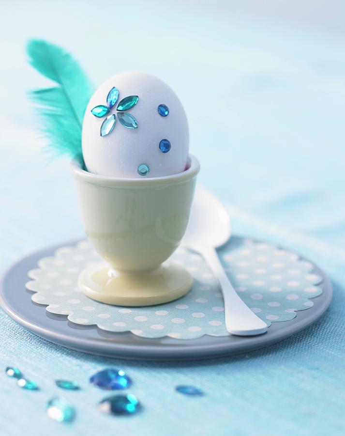 White Egg Decorated With Blue Rhinestones & Feather In Egg Cup Photograph by Jan-peter Westermann