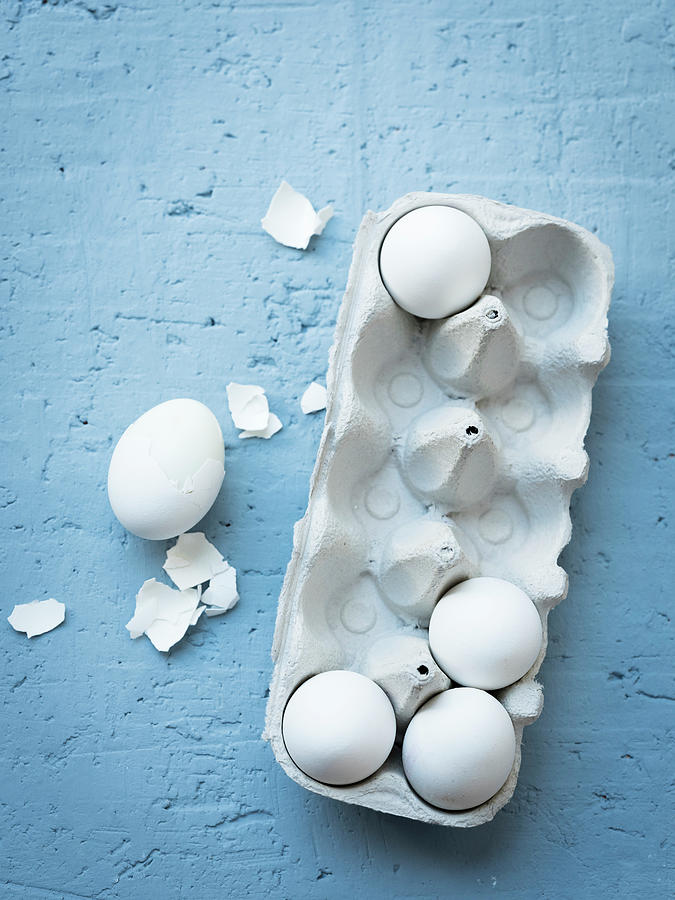 White Eggs In An Egg Box Next To A Boiled, Partially Shelled Egg Photograph by Manuela Rther