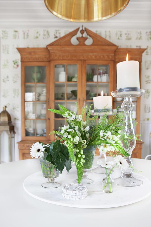 White Flowers And Lit Candles In Candlesticks On Table In Front Of Antique, Glass-fronted Cabinet Photograph by Annette Nordstrom