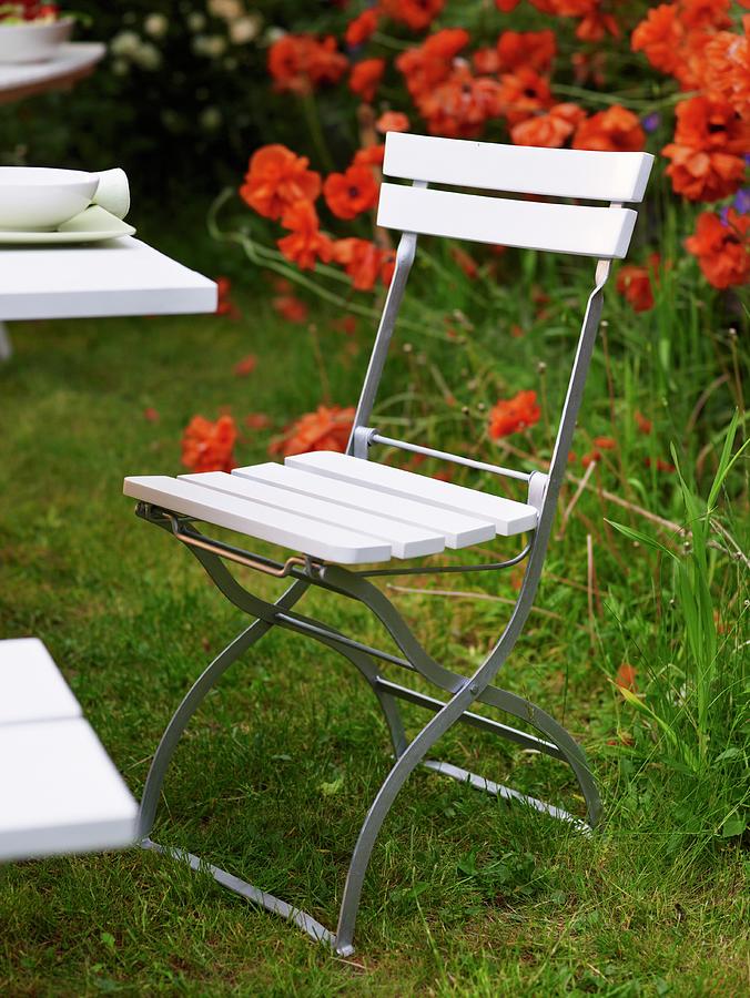 White Folding Chair In A Garden With Red Flowers Photograph by Per Magnus Persson